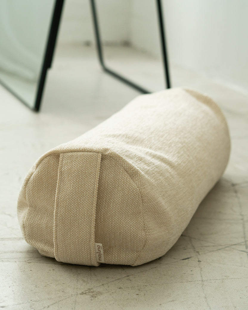 Mayuna Yogabolster in Sand, zylindrische Form mit Tragegriff, auf hellem Boden